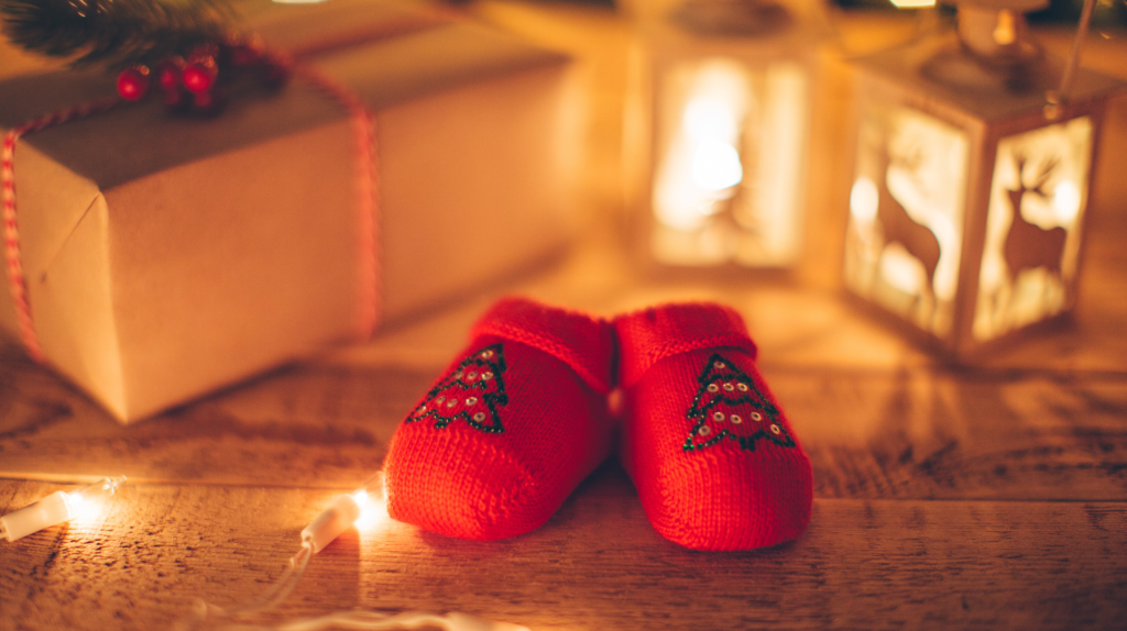 Red baby shoes by Christmas present and lanterns