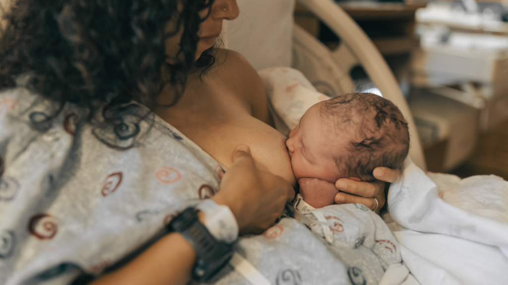 woman breastfeeding newborn in a hospital bed