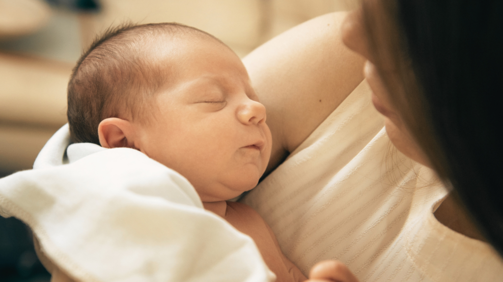 woman holding newborn wrapped in white blanket